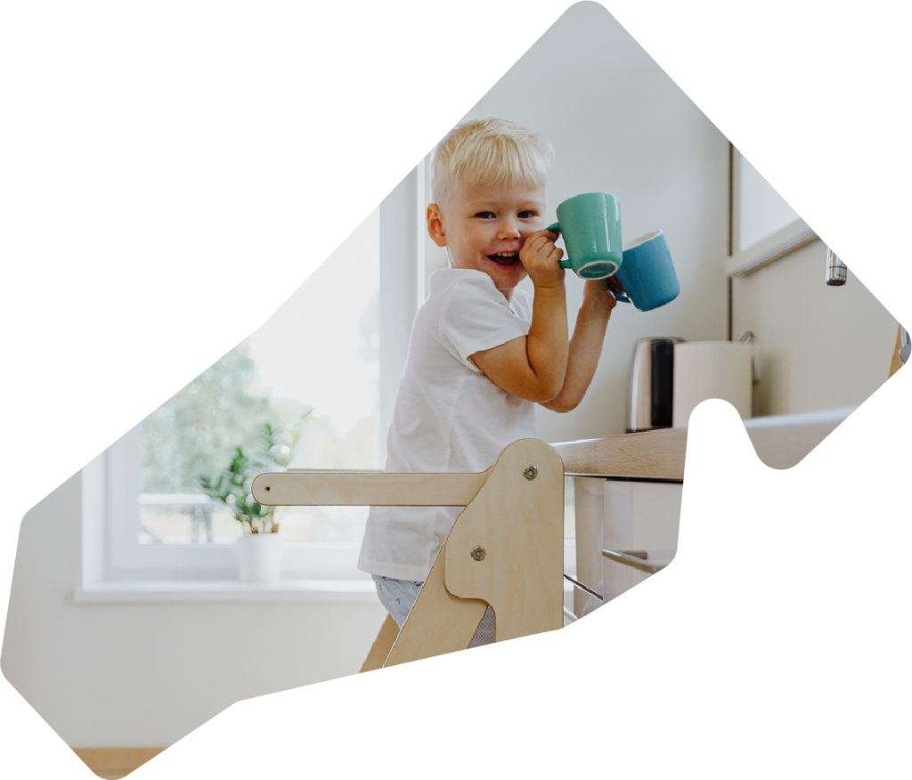 kid on a learning tower playing in the kitchen