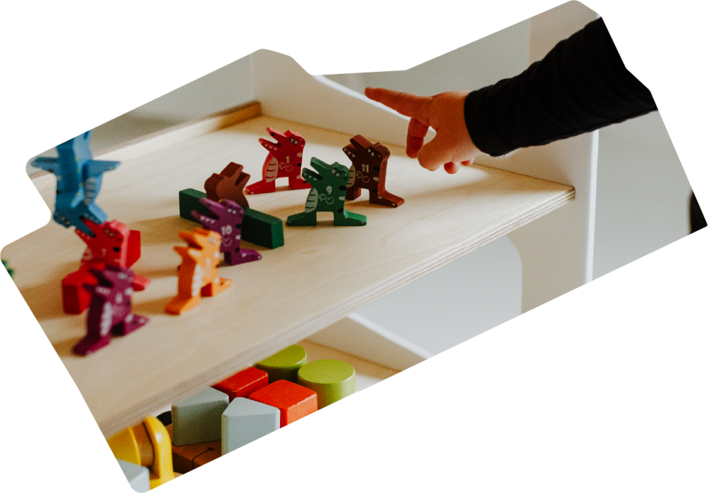 A kid playing with toys that are located on a Montessori bookshelf 