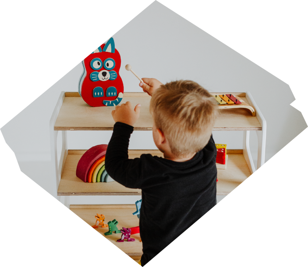 Kid playing with toys that are located on a Montessori bookshelf 